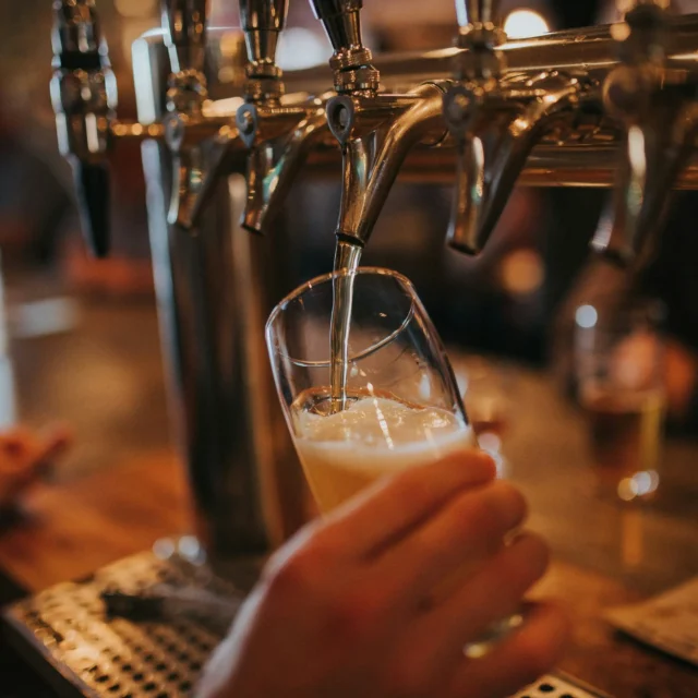 Beer being poured from a bar tap into a glass held by hand