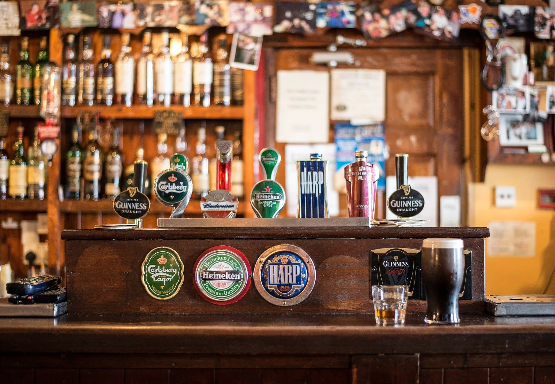 Traditional pub bar with beer taps including Guinness, Carlsberg, Heineken and Harp, shelves of spirits behind