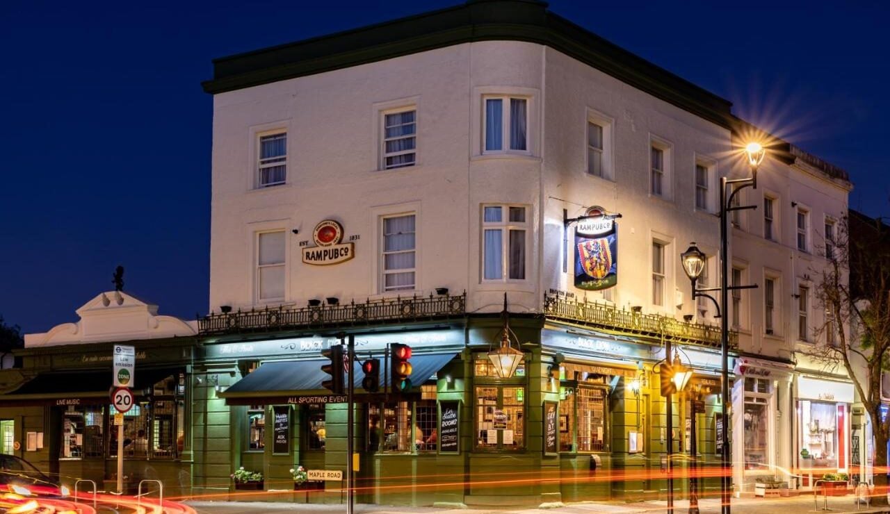 The Black Horse pub on a street corner at night, lit windows, hanging sign, and light trails from passing traffic