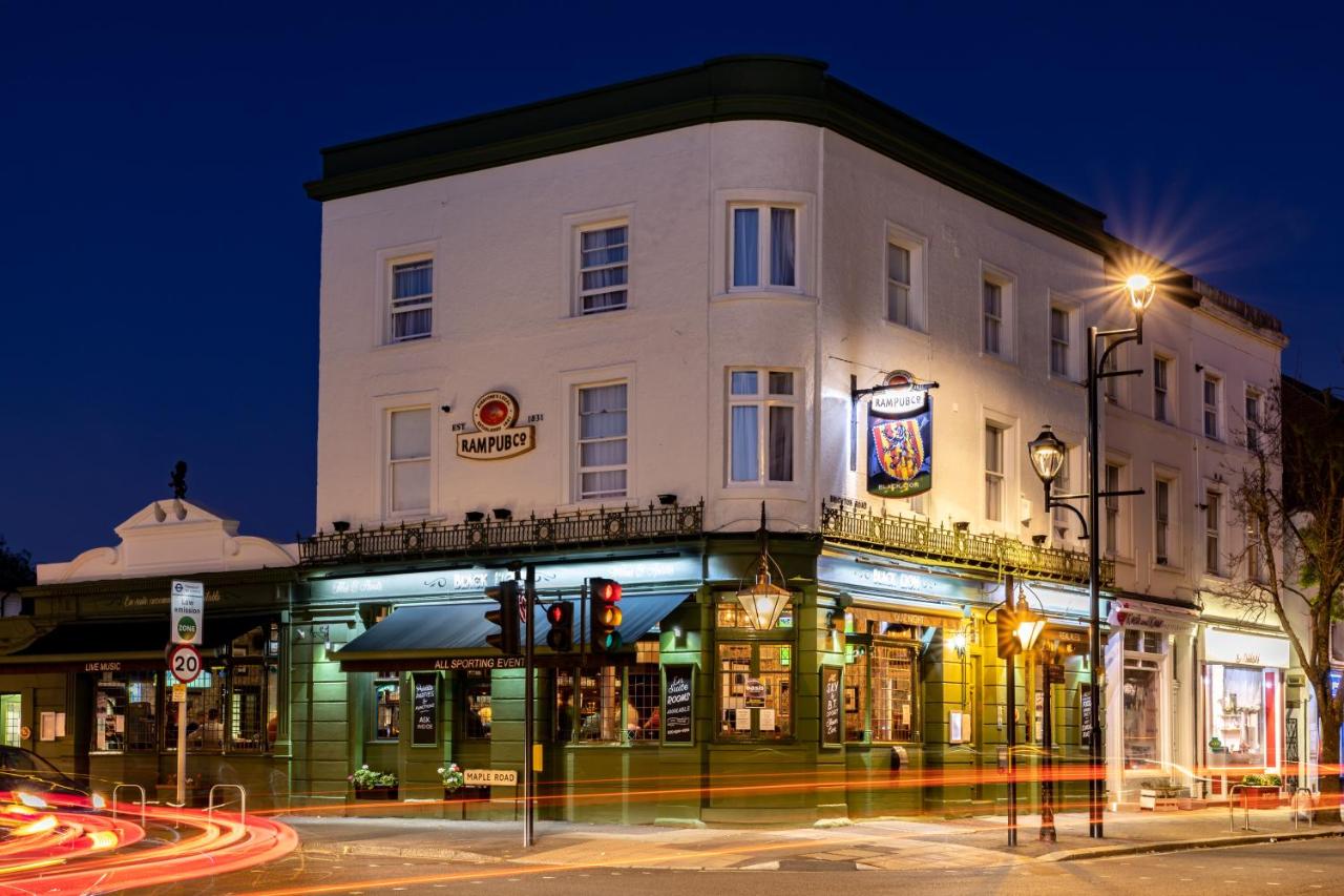 The Black Horse pub on a street corner at night, lit windows, hanging sign, and light trails from passing traffic