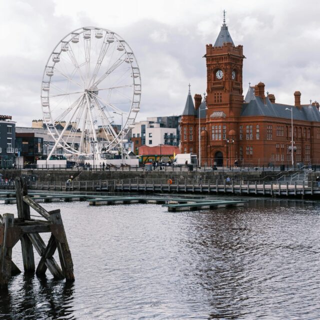 Cardiff Bay waterfront with the Pierhead Building's clock tower and a large Ferris wheel beside the harbour