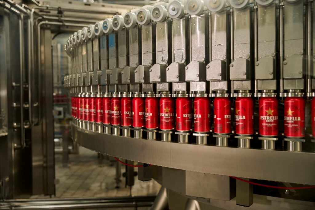 Estrella Damm cans moving along a filling and sealing line in a bottling factory